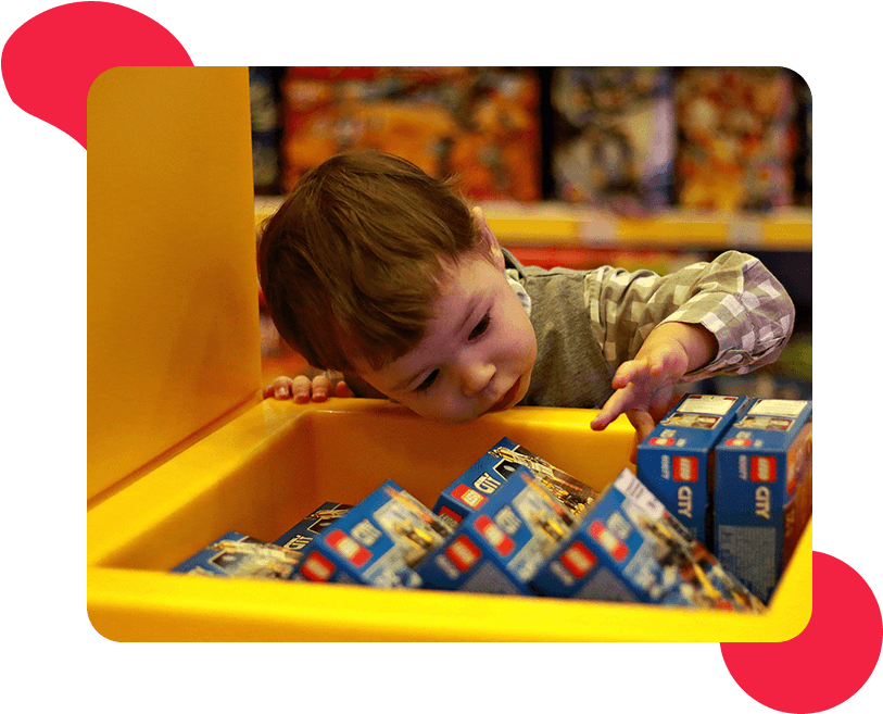 Young boy reaching for toy boxes.