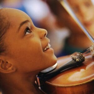 Girl smiling while playing violin.