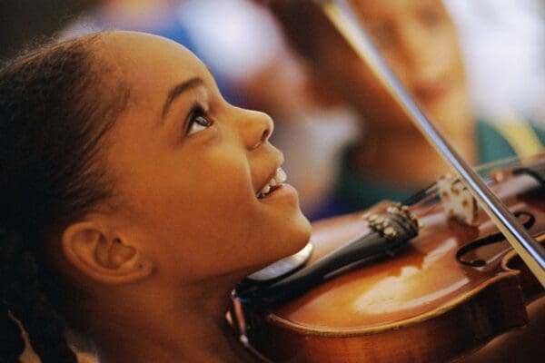 Girl smiling while playing violin.