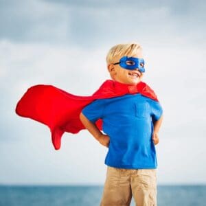 Smiling boy in red cape and mask.