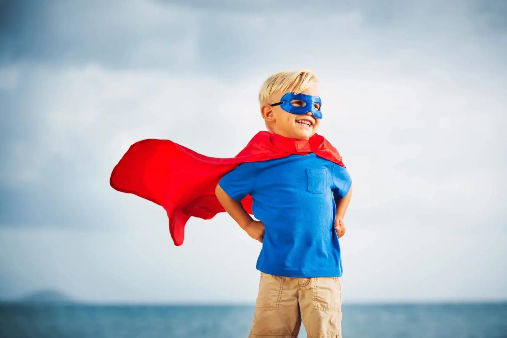 Smiling boy in red cape and mask.