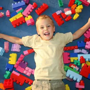 Boy surrounded by colorful building blocks.