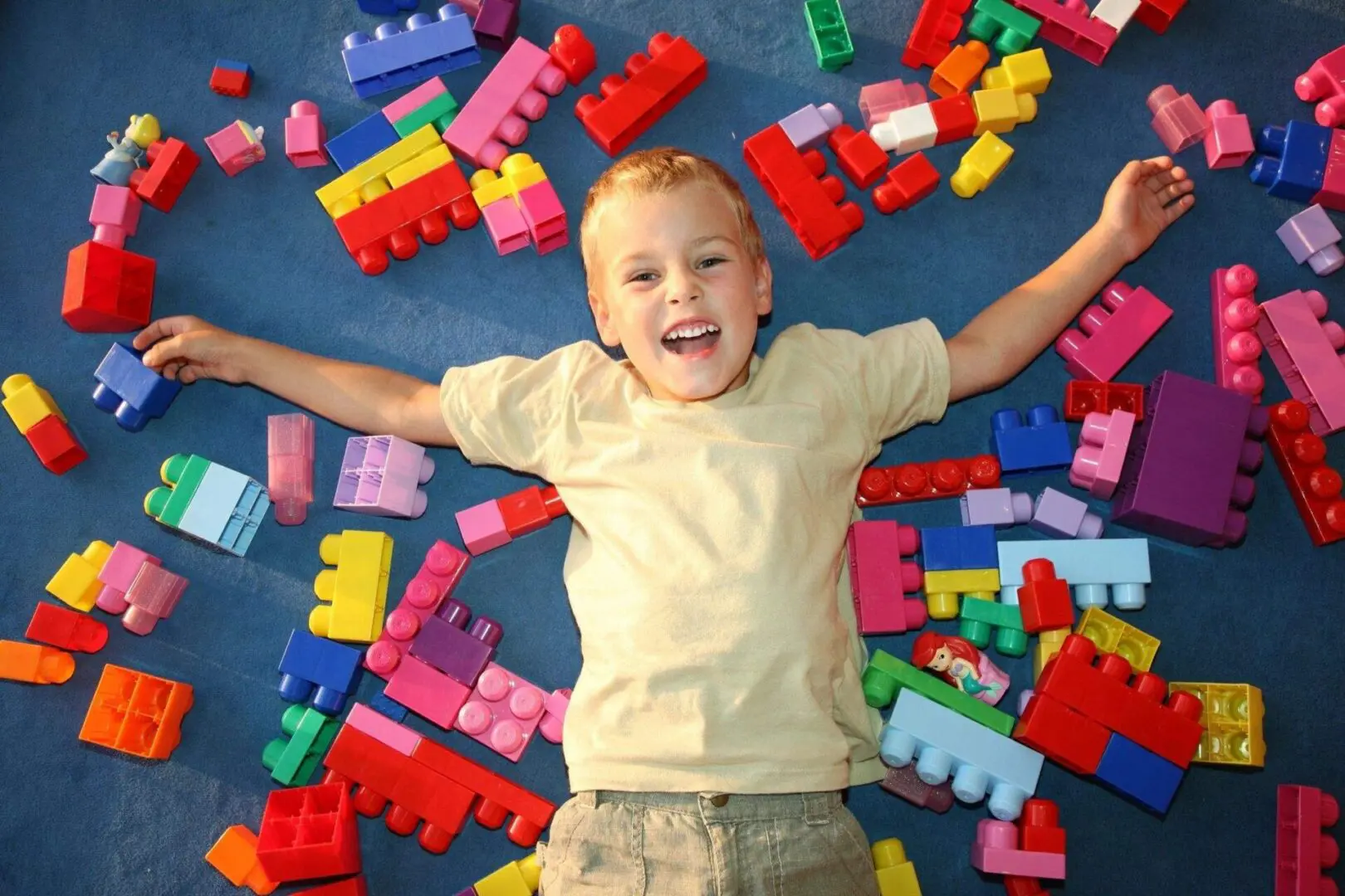 Boy surrounded by colorful building blocks.